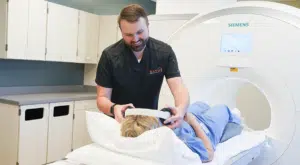 technologist putting headphones on a patient before they go into an mri