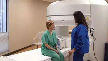 Tech explains Open MRI to patient sitting on MRI bed