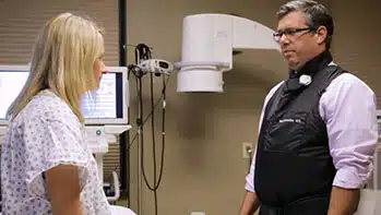 Patient in scrubs and doctor in exam room