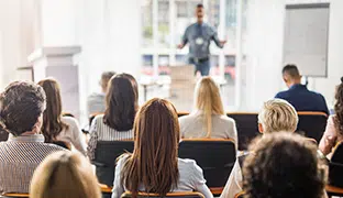Group of people sitting in a conference room as someone presents