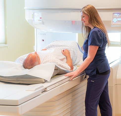 smiling technologist helping patient into oasis scanner