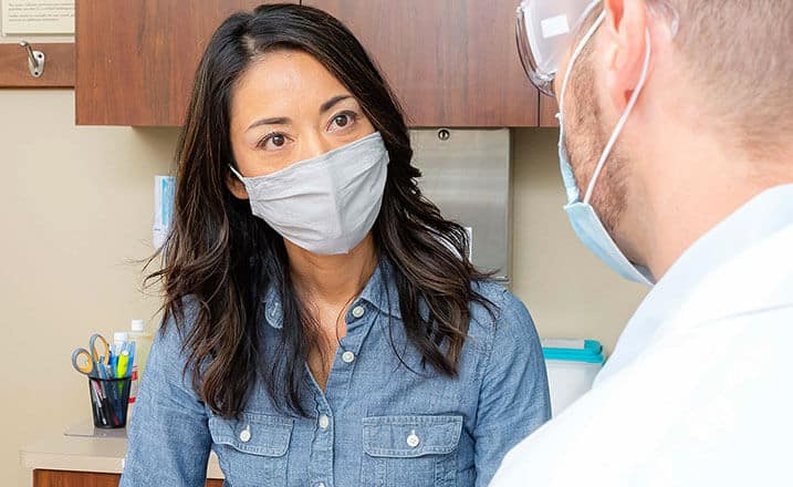 Radiologist consulting with a patient while wearing a face mask.
