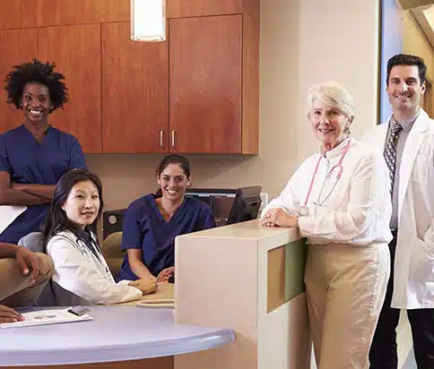 Diverse group of six employees sitting at a clinic desk.